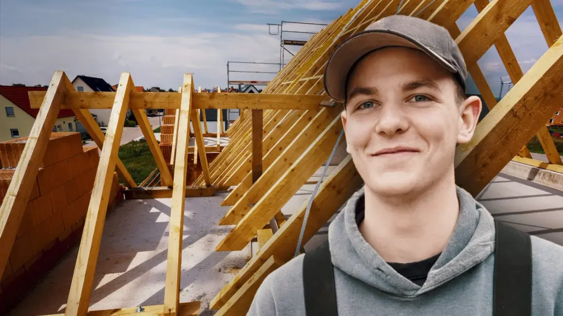 Junger Mann mit Kappe lächelt vor Dachstuhl. Ausbildung Zimmermann Gehalt ist ein guter Start.