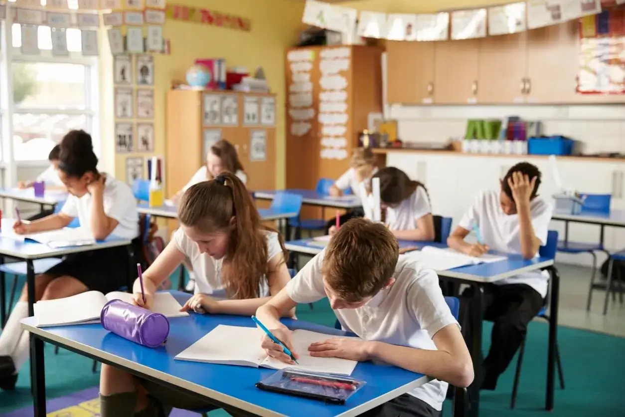 Sch&uuml;ler konzentriert in einem hellen Klassenzimmer, das auf healing classrooms hindeutet.