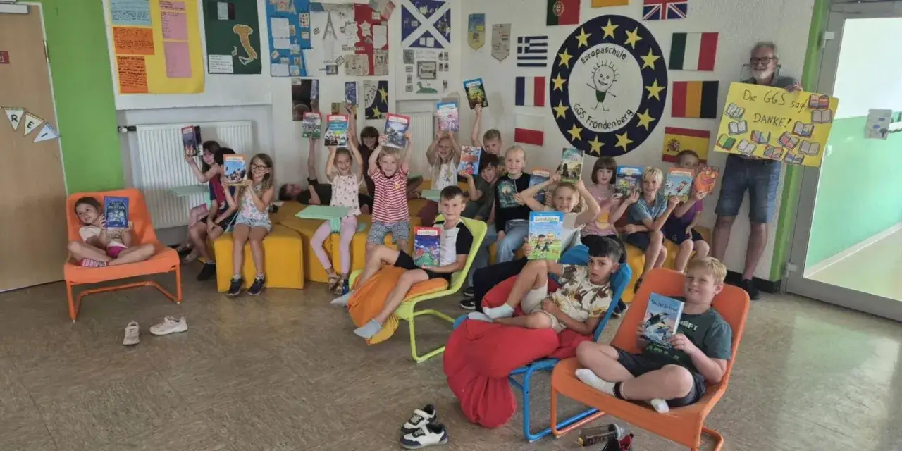 Kinder der Europaschule Fröndenberg zeigen stolz ihre Bücher. Ein Lehrer hält ein Dankeschön-Schild. Förderung der Basiskompetenzen Grundschule durch Lesen.