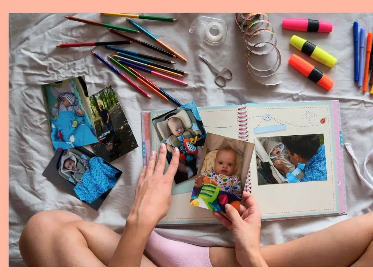 Hände gestalten ein Fotoalbum mit Babybildern, Buntstiften und Schere. Erinnerungen an Ferienerlebnisse Grundschule werden lebendig.