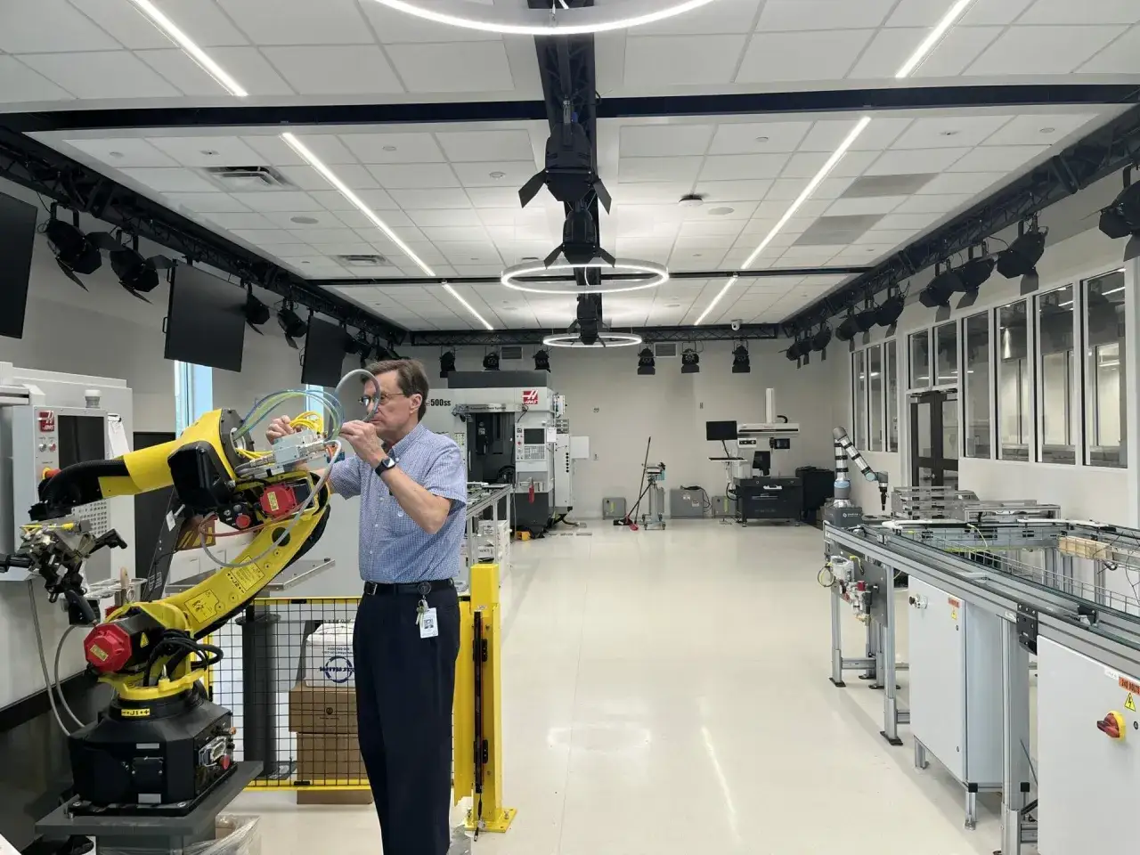 Mann arbeitet an einem Roboterarm in einem modernen Labor, das für das Robotik Studium ausgestattet ist.
