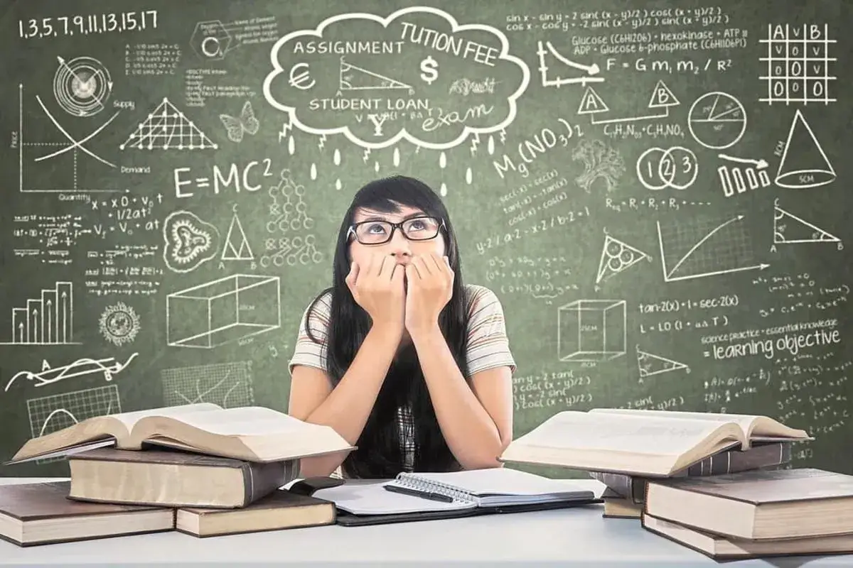 Ein M&auml;dchen mit nerv&ouml;sen Fingern blickt auf, umgeben von B&uuml;chern und Formeln. Der Leistungsdruck Schule scheint ihr ins Gesicht geschrieben.