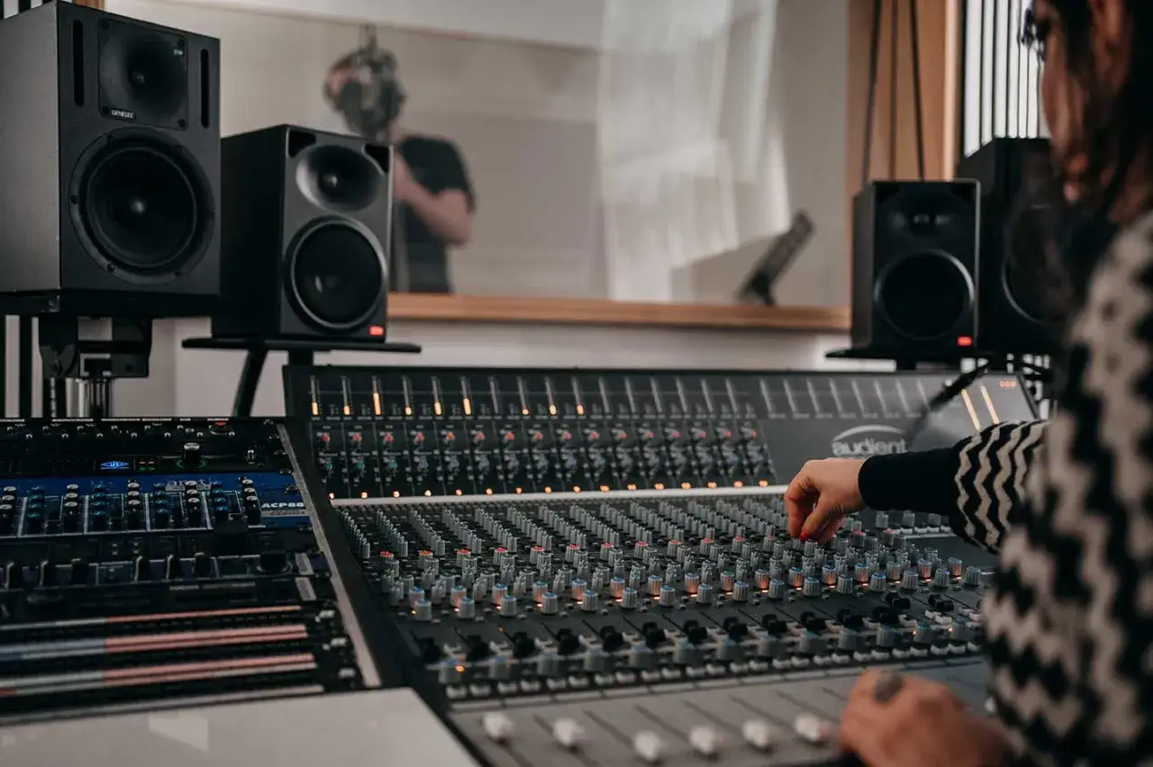 Eine Person am Mischpult, umgeben von Lautsprechern. Perfekt f&uuml;r das Musikproduktion Studium.